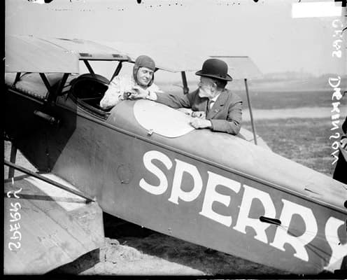 Lawrence Sperry seated in an airplane, shaking hands with fellow aviator Charles Dickinson, Chicago, 1923.