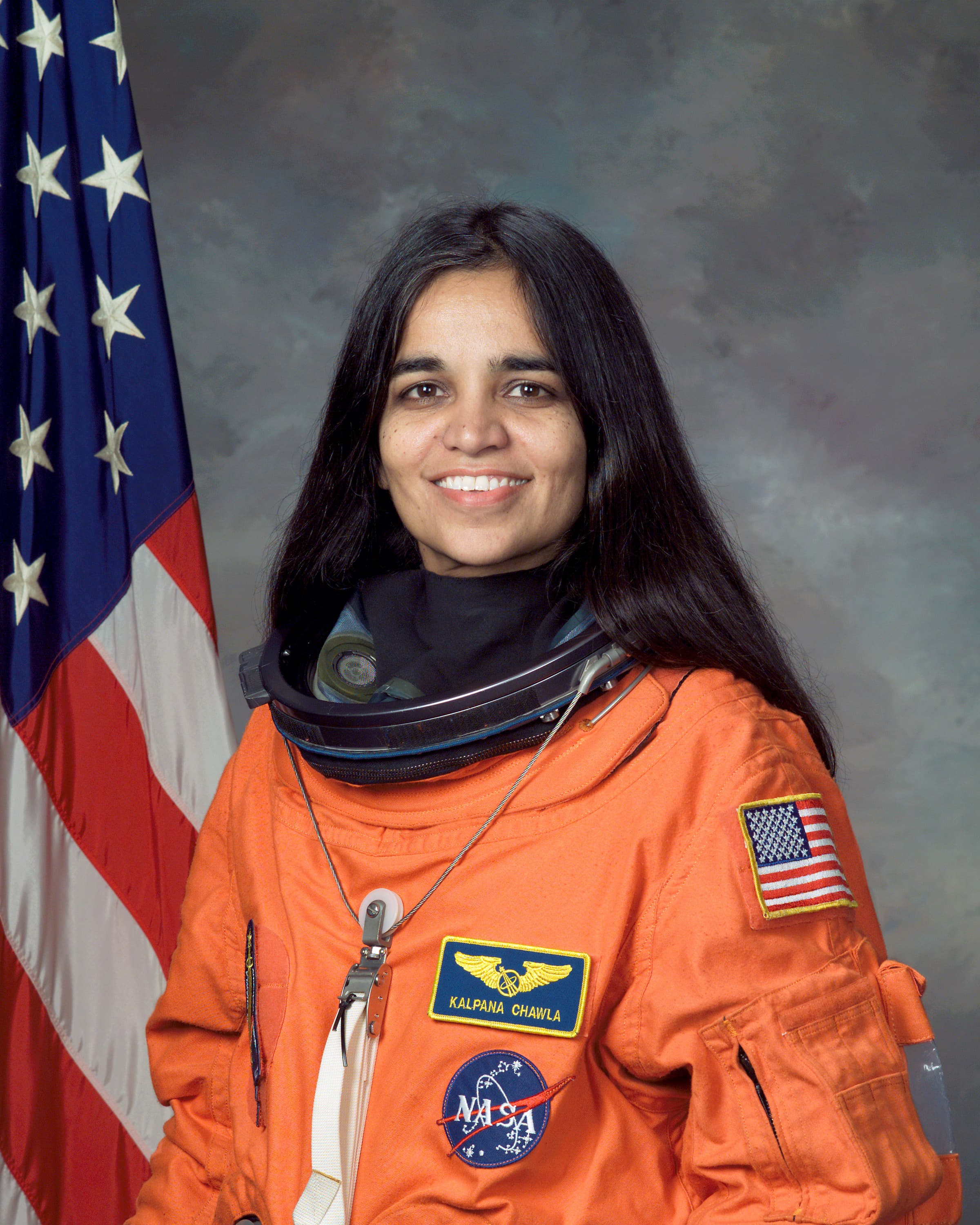 Official NASA portrait of astronaut Kalpana Chawla in an orange flight suit.